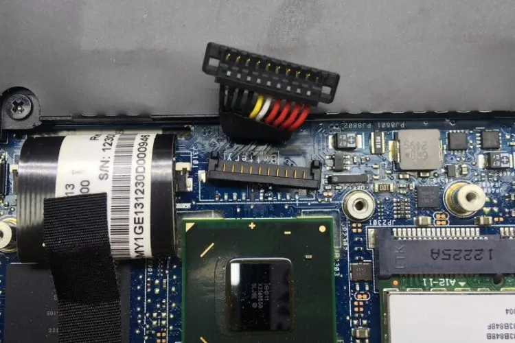 The image appears to show an internal view of an ASUS laptop. The focus is on the battery connector, which is unplugged from the motherboard.